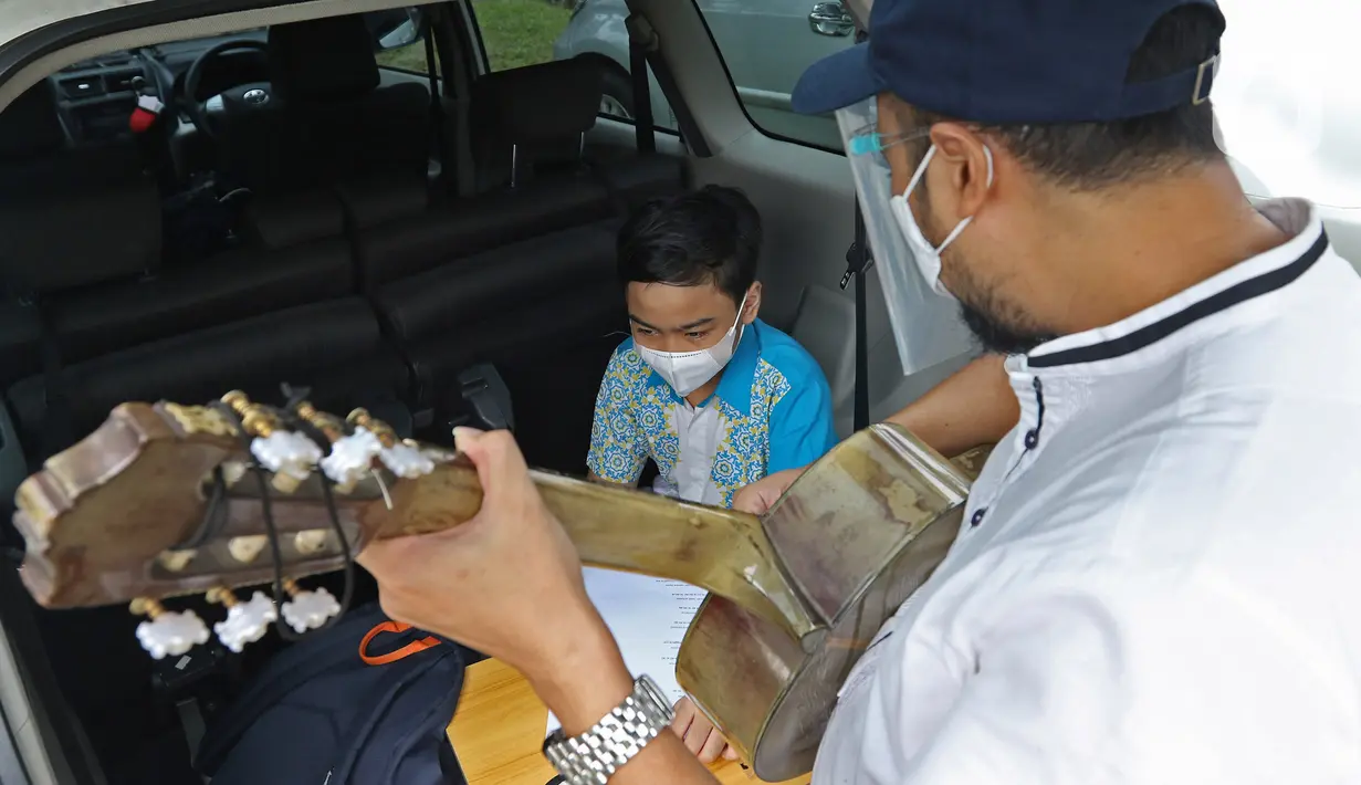 Orang tua murid bermain gitar saat mengikuti DRIL dengan konsep pembelajaran di ruang terbuka di Jakarta, Senin (5/4/2021). Kegiatan tersebut dilakukan guna menghidupkan semangat belajar siswa dengan tetap mengikuti protokol kesehatan secara ketat. (Liputan6.com/Herman Zakharia)