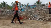 Polisi dengan bantuan anjing pelacak bersiap mencari korban gempa bumi di bangunan Rumah Sakit Mitra Manakarra yang runtuh di Mamuju, Minggu (17/1/2021). Polri mengerahkan enam ekor K-9 untuk membantu menangani dampak gempa bumi di Majene dan Mamuju, Sulawesi Barat. (Liputan6.com/Abdul Rajab Umar)