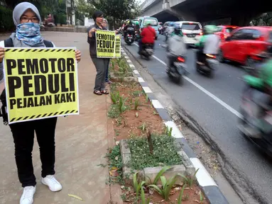 Aktivis Koalisi Pejalan Kaki melakukan aksi peduli pejalan kaki di kawasan pedestrian Kasablanka, Jakarta, Kamis (22/8). Mereka menyerukan agar tidak menggunakan trotoar sebagai tempat parkir dan berjualan.(Liputan6.com/JohanTallo)