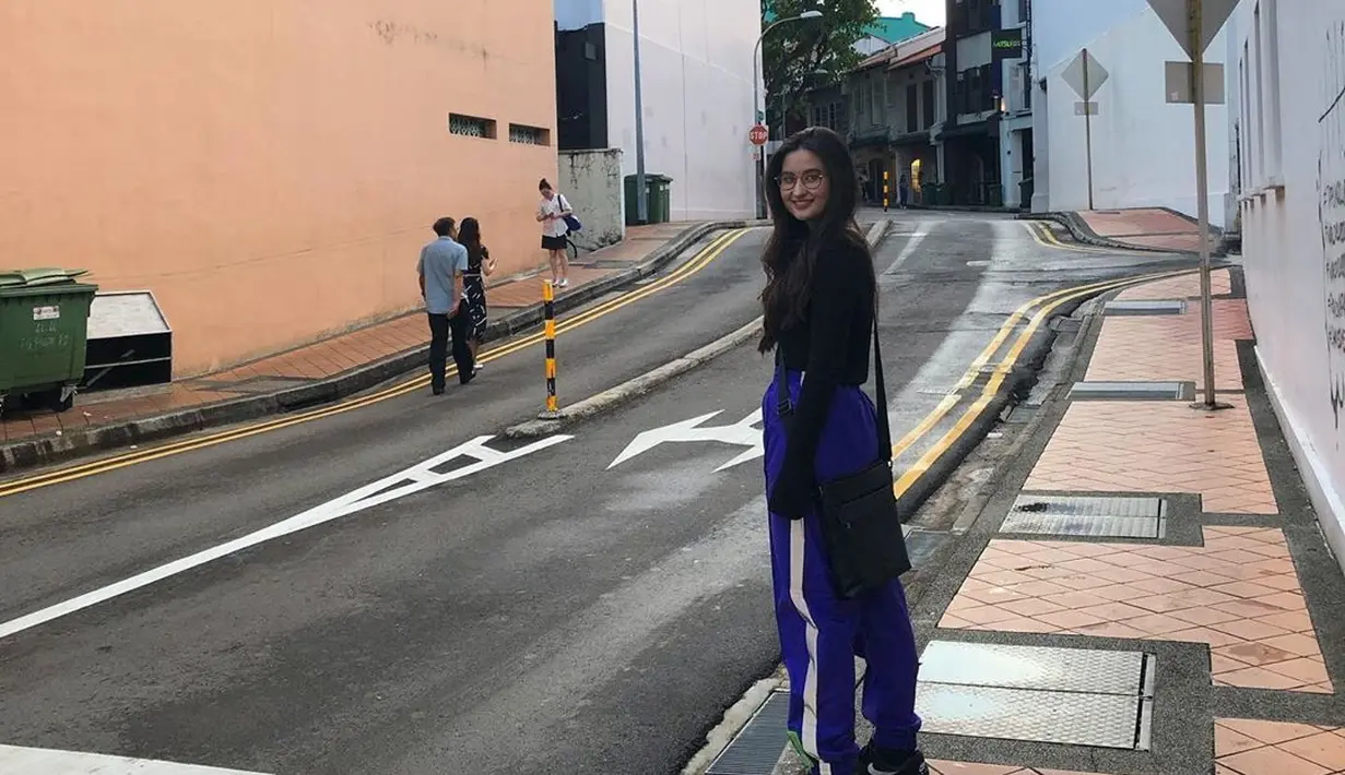 Wanita yang memiliki panggilan Meni ini menggunakan baju hitam dan celana berwarna biru dengan garis putih. Berpose di sebuah jalan, sepatu hitam dan tas hitamnya tampak serasi dengan rambutnya yang berwarna hitam pekat. (Liputan6.com/IG/@stephaniepoetri)