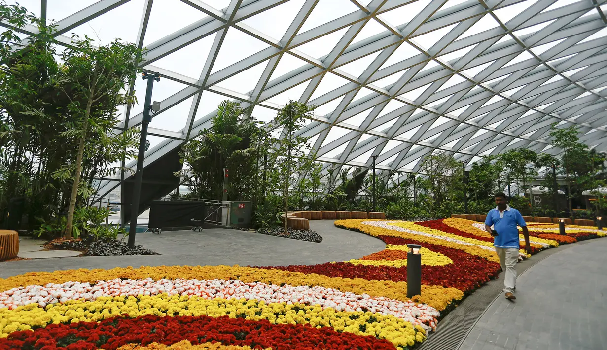 Pengunjung berjalan melewati taman bunga di Jewel Changi Airport, Singapura, 11 April 2019. Jewel Changi Airport memiliki hutan tiruan yang menyimpan lebih dari 2.000 pepohonan dengan 120 spesies tanaman dari berbagai negara. (REUTERS/Feline Lim)
