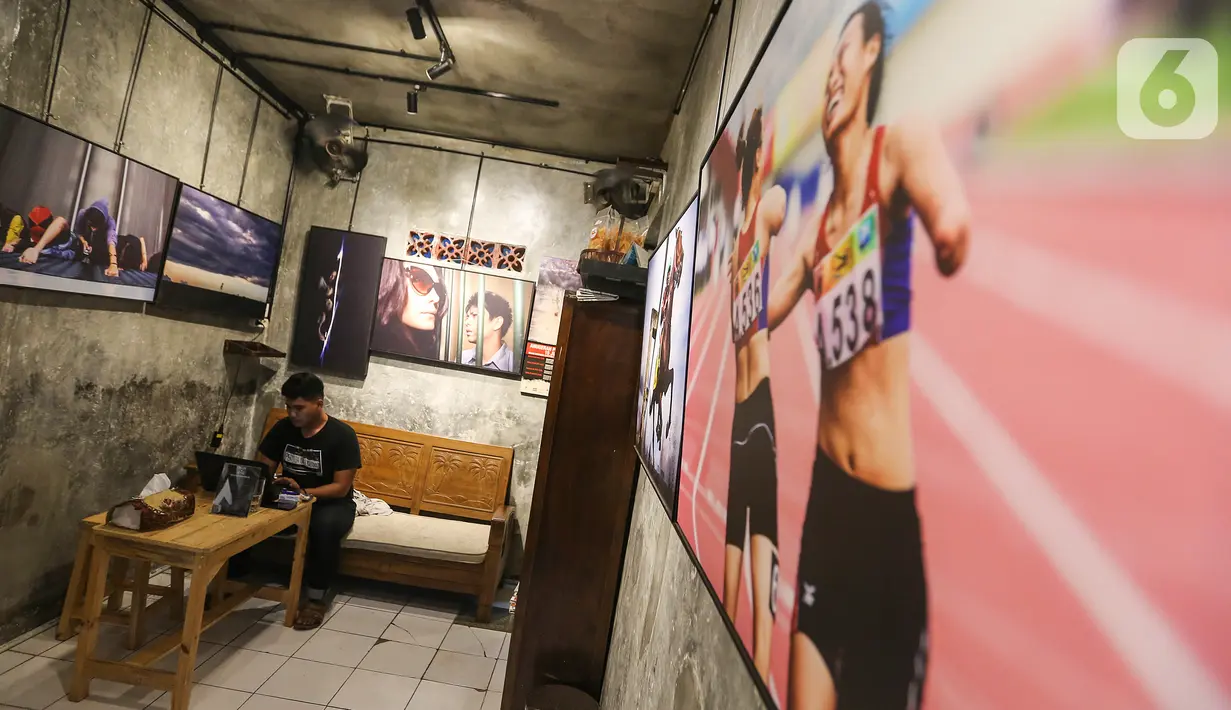 Pengunjung menikmati kopi sambil bekerja di kedai Ngopi di Halaman Jalan Pulo Kamboja, Kebayoran Lama, Jakarta, Selasa (12/01/2021). Kedai yang menawarkan konsep galeri foto dan sejumlah koleksi buku fotografi bisa menginspirasi pengunjung yang datang sambil nongkrong. (Liputan6.com/Fery Pradolo)