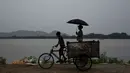 Seorang anak membonceng adiknya menggunakan sepeda gerobak saat hujan mengguyur Gauhati, India, Selasa (30/5). Beberapa negara bagian di India timur laut mengalami hujan deras sebagai efek topan Mora yang melanda selatan Bangladesh. (AP Photo/Anupam Nath)