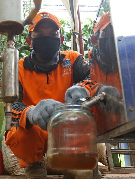 Petugas PPSU Kelurahan Kota Bambu Selatan menampung solar hasil olahan sampah plastik di Bank Sampah Hasil Berkah, Jakarta, Kamis (11/11/2021). Sampah plastik dikonversi menjadi solar menggunakan alat mesin pirolisis untuk mengurangi pencemaran lingkungan. (Liputan6.com/Herman Zakharia)
