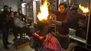 Ramadan Edwan, seorang tukang cukur asal Palestina, menggunakan api untuk mencukur rambut pelanggannya di sebuah barbershop di kamp pengungsian Rafah, di selatan Jalur Gaza, Rabu (1/2). (MAHMUD HAMS/AFP)