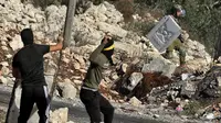 Pengunjuk rasa Palestina melemparkan batu saat bentrok dengan pasukan keamanan Israel di Desa Kfar Qaddum, dekat pemukiman Yahudi Kedumim, Tepi Barat, 10 Desember 2021. Pengunjuk rasa memprotes pengambilalihan tanah oleh Israel. (Jaafar ASHTIYEH/AFP)