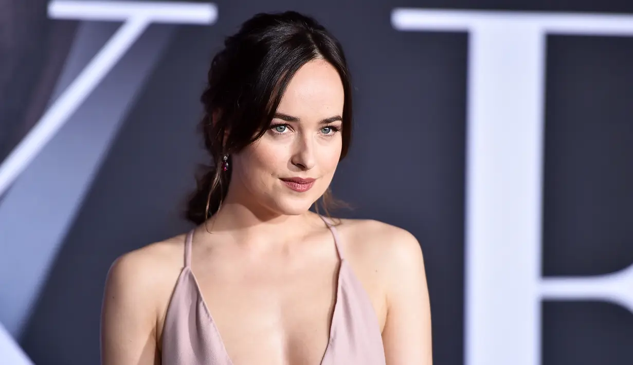 Pose Dakota Johnson saat tiba menghadiri pemutaran film perdana "Fifty Shades Darker" di The Theatre di Ace Hotel di Los Angeles, AS (2/2). Dakota Johnson tampil cantik dengan gaun seksi berwarna pink. (Alberto E. Rodriguez/Getty Images/AFP)