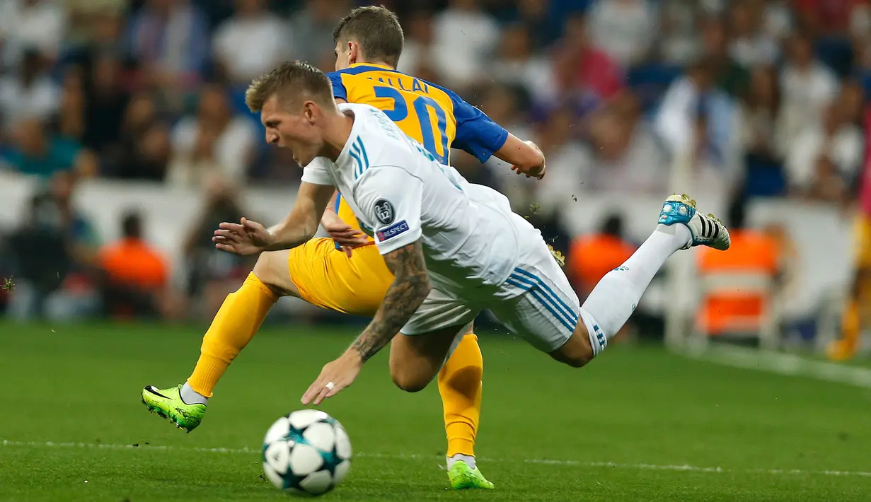 Gelandang Real Madrid, Toni Kroos saat dilanggar pemain APOEL Nicosia, Roland Sallai saat bertanding pada penyisihan Grup H Liga Champions di stadion Santiago Bernabeu, Spanyol, (13/9). Madrid menang telak 3-0 atas APOEL. (AP Photo/Francisco Seco)