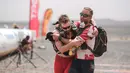 Seorang peserta membantu rekan satu timnya saat akan melewati garis finish dalam kompetisi Marathon des Sables ke-33 di gurun Sahara, Maroko (13/4). (AP Photo / Mosa'ab Elshamy)