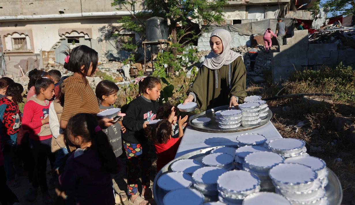Sebagai informasi, laporan Global Report on Food Crises (GRFC) 2026 menyebutkan, Gaza termasuk wilayah dengan tingkat kelaparan ekstrem. Tampak dalam foto, seorang wanita Palestina, Aya Zeid, membagikan paket makanan kepada anak-anak pengungsi sebagai kegiatan amal di daerah Al-Tuam, sebelah barat Jabalia, Jalur Gaza Utara pada Rabu 6 Mei 2026. (Omar AL-QATTAA/AFP)