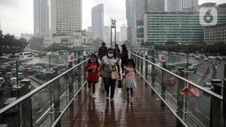 Warga berjalan di JPO Bundaran HI, Jakarta, Rabu (28/12/2022). Walau sempat disebutkan ada potensi badai dahsyat yang melanda kawasan Jakarta–Bogor–Depok–Tangerang–Bekasi (Jabodetabek) pada hari ini, warga Jakarta terpantau masih banyak beraktivitas di luar ruangan. (Liputan6.com/Faizal Fanani)