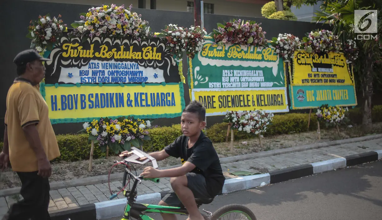 Warga melintas dekat karangan bunga atas meninggalnya istri Indro Warkop, Nita Octobijanthy yang terpajang di rumah duka kawasan Pulo Mas, Jakarta, Rabu (10/10). Istri Indro Warkop meninggal di usia 59 tahun akibat kanker. (Liputan6.com/Faizal Fanani)