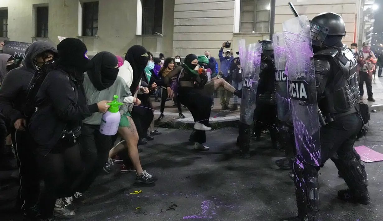 Sejumlah perempuan bentrok dengan polisi saat pawai memperingati Hari Perempuan Internasional di Quito, Ekuador, 8 Maret 2022. (AP Photo/Dolores Ochoa)