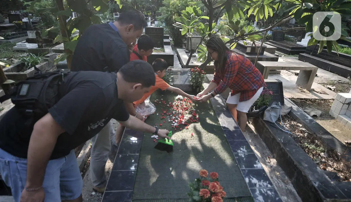 Keluarga menaburkan bunga ke makam saat ziarah di kompleks pemakaman Gereja Tugu, Semper, Jakarta, Senin (23/12/2019). Warga keturunan Portugis melakukan ziarah ke makam keluarga mereka untuk merawat makam sekaligus mendoakan keluarga yang telah meninggal dunia. (merdeka.com/Iqbal Nugroho)