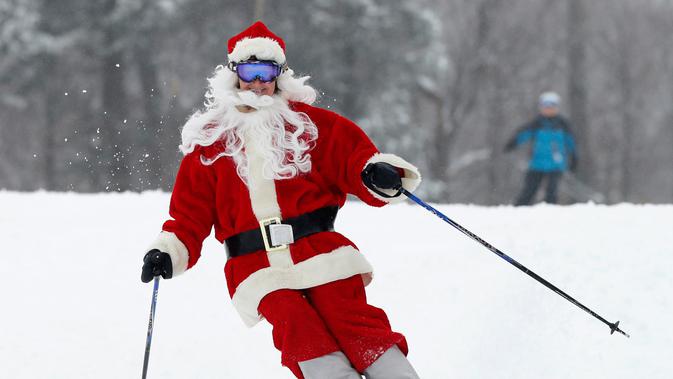 Pemain ski berpakaian Santa Claus menuruni lereng gunung saat Santa Sunday ke-19 di Newry, Maine, AS, Minggu (2/12). Keuntungan acara Santa Sunday digunakan untuk amal. (AP Photo/Robert F. Bukaty)