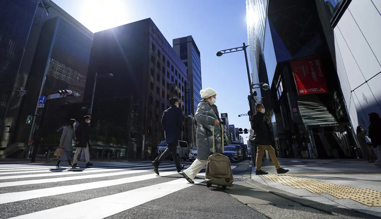 Orang-orang yang mengenakan masker pelindung untuk membantu mengekang penyebaran COVID-19 menyeberangi jalan di Tokyo, Jepang, Kamis, (4/2/2021). Tokyo mengonfirmasi lebih dari 730 kasus baru COVID-19 pada 4 Februari 2021. (AP Photo/Eugene Hoshiko)