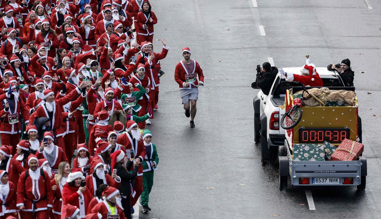 Sebagai informasi, kegiatan ini dilakukan secara rutin tiap tahunnya oleh salah satu grup department store terbesar di Spanyol. Tampak dalam foto, ribuan pelari yang mengenakan kostum Santa Claus berpartisipasi dalam edisi ke-14 lomba Santa Claus, sebuah lari santai sejauh 4,5 km melalui jalan-jalan Madrid pada Minggu 21 Desember 2025. (OSCAR DEL POZO/AFP)