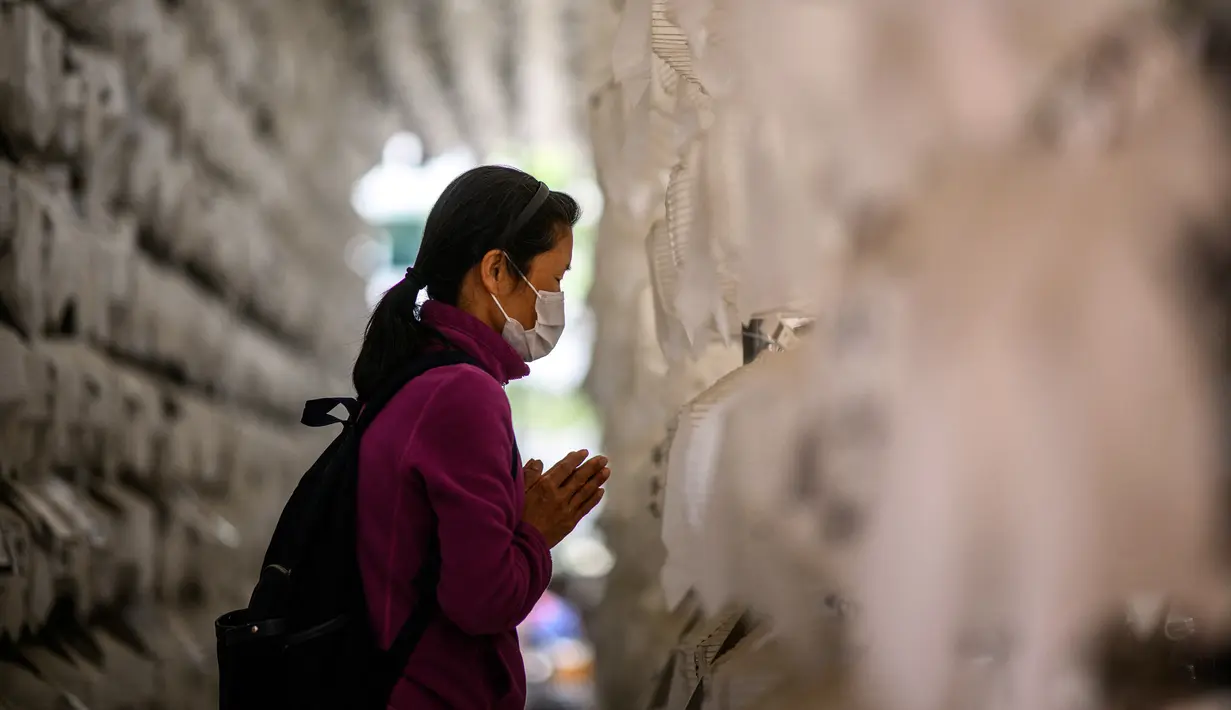 <p>Seorang wanita berdoa di depan lentera teratai putih dengan nama dan doa tertulis pada atasnya setelah kebaktian untuk merayakan ulang tahun Buddha di Kuil Jogye, Seoul, Korea Selatan, Minggu (8/5/2022). (ANTHONY WALLACE/AFP)</p>