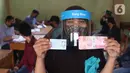 Warga menunjukkan uang dan KTP usai mendapatkan bantuan sosial (bansos) yang diberikan Pemerintah Provinsi Banten di Pinang, Tangerang, Jumat (1/5/2020). Bansos berupa uang tunai sebesar Rp 600 ribu tersebut diberikan kepada warga yang terdampak virus corona COVID-19. (Liputan6.com/Angga Yuniar)