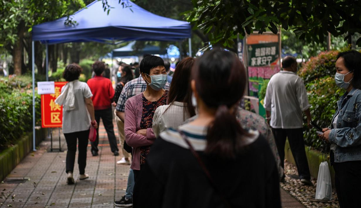 Warga mengenakan masker menunggu dalam barisan untuk tes virus corona di lingkungan di Wuhan, provinsi Hubei, China, Jumat (15/5/2020). Pihak berwenang Kota Wuhan menggelar tes massal terhadap 11 juta warganya untuk mencegah gelombang kedua pandemi Covid-19. (Hector RETAMAL/AFP)