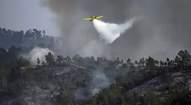 Sebuah pesawat pemadam kebakaran menjatuhkan air di atas api di Odeceixe, selatan Portugal, Selasa (8/8/2023). Ratusan petugas pemadam kebakaran berusaha memadamkan api yang berkobar di Portugal selatan yang telah menghanguskan ribuan hektare lahan dan menyebabkan sekitar 1.400 orang dievakuasi untuk berjaga-jaga. (Patricia DE MELO MOREIRA/AFP)