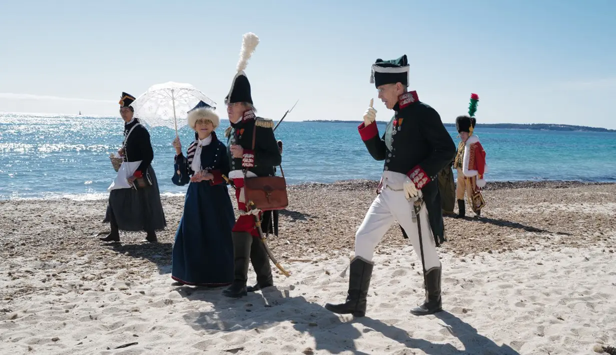 Orang-orang yang mengenakan kostum era Napoleon Bonaparte berjalan di pantai dalam rangka peringatan 200 tahun kematian Napoleon Bonaparte di Saint-Helene, Golfe-Juan, Prancis, 16 Maret 2021. Napoleon lebih satu dasawarsa memimpin Prancis melawan koalisi dalam Perang Napoleonis. (Valery HACHE/AFP)