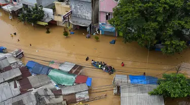 Warga mengungsi menggunakan perahu di kota Dayeuhkolot yang terendam banjir di Bandung pada 12 Januari 2024. (TIMUR MATAHARI/AFP)