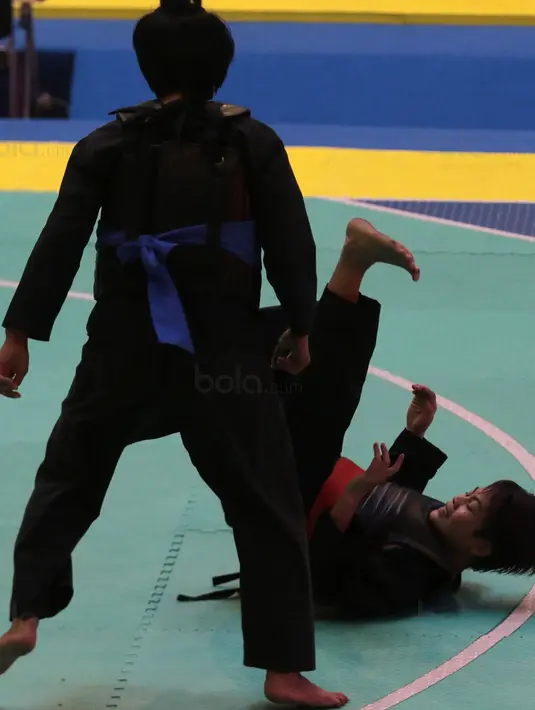 Pesilat Indonesia, Octaviani Nirmalasari (kanan) jatuh saat melawan pesilat Laos, Olahthai Sounthavong pada semifinal Test Event Pencak Silat 2018 di Padepokan Silat TMII, Jakarta, (12/2/2018). Oktaviani menang 5-0. (Bola.com/Nick Hanoatubun)