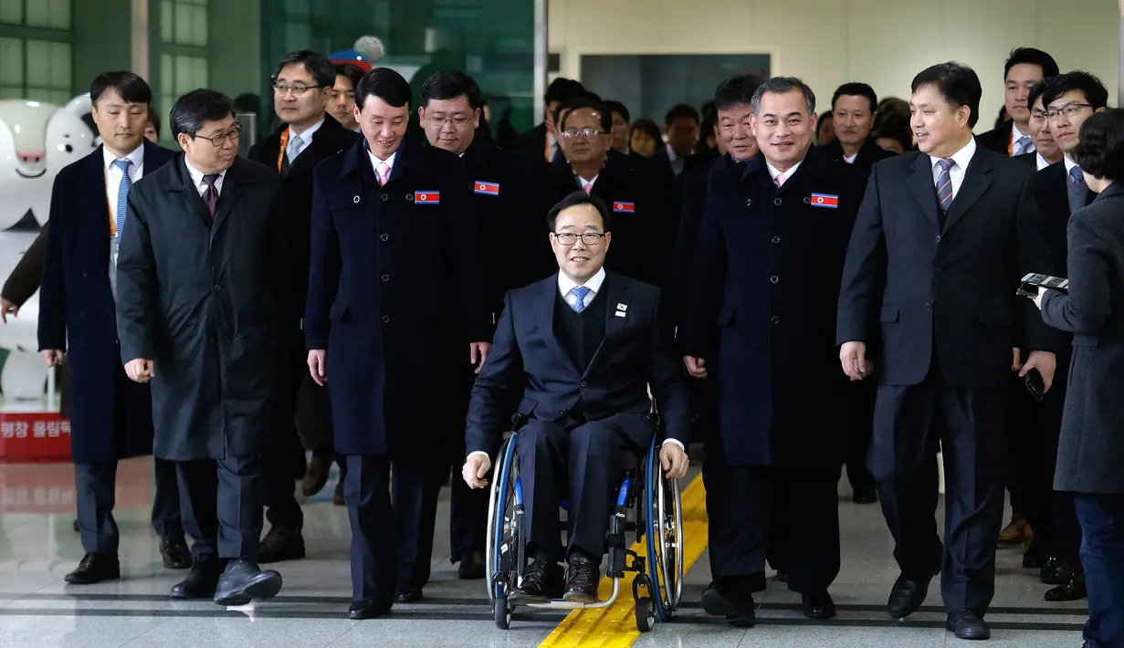 Direktur Komite Paralimpiade Pyeongchang 2018, Lim Chan-kyu (tengah) mengawal delegasi Korea Utara saat mereka tiba di Kantor Transit Korea, dekat Zona Demiliterisasi, Paju, Korea Selatan, Rabu (7/3). (Ahn Young-joon/POOL/AFP)