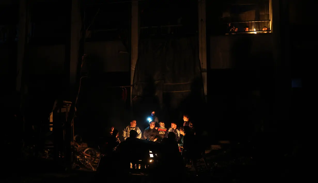 Warga Palestina duduk di dekat perapian di tengah reruntuhan rumah mereka di Jabalia di Jalur Gaza utara pada 18 Februari 2025. (Omar AL-QATTAA/AFP)