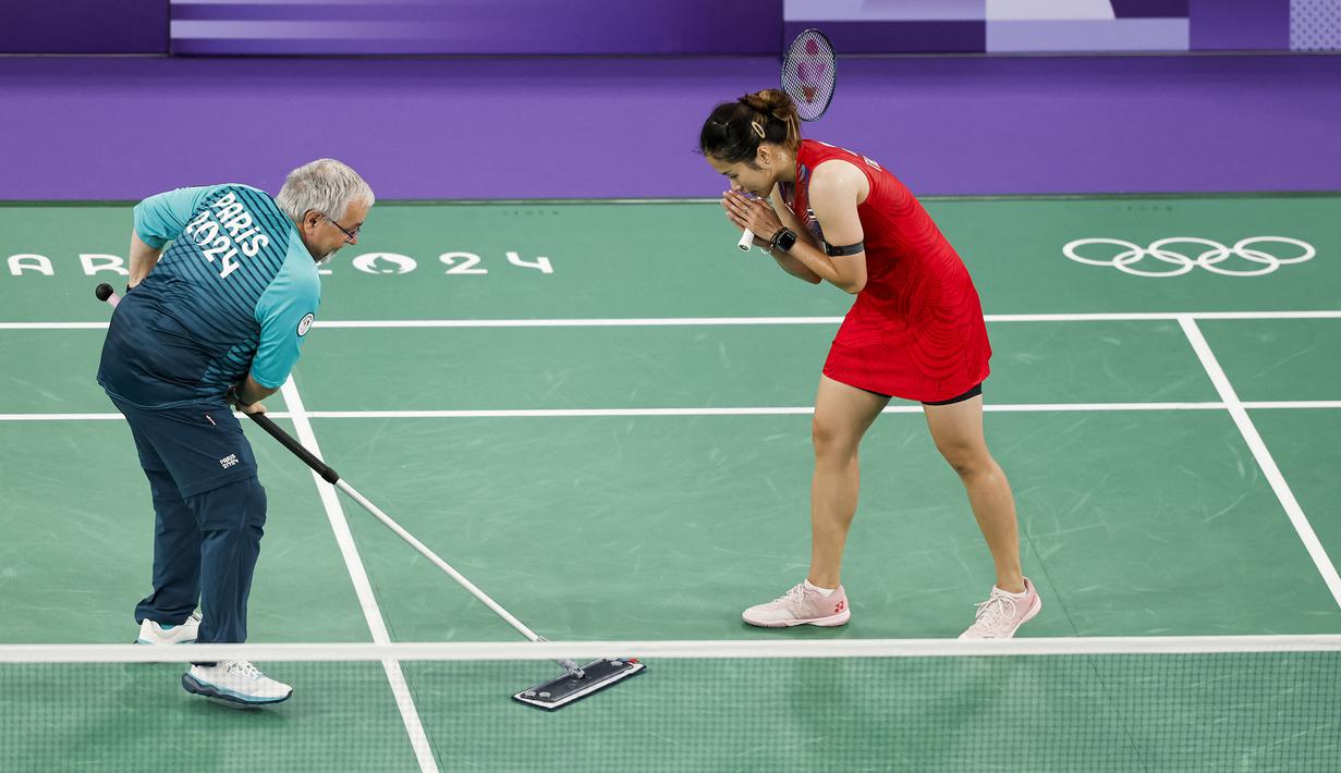 Seorang volunter sedang memberishkan keringan pebulu tangkis putri Thailand, Ratchanok Intanon saat pertandingan grup Olimpiade Paris 2024 melawan atlet Belgia, Lianne Tan di Porte de la Chapelle Arena, Paris, Prancis pada 30 Juli 2024. (AFP/Luis Tato)