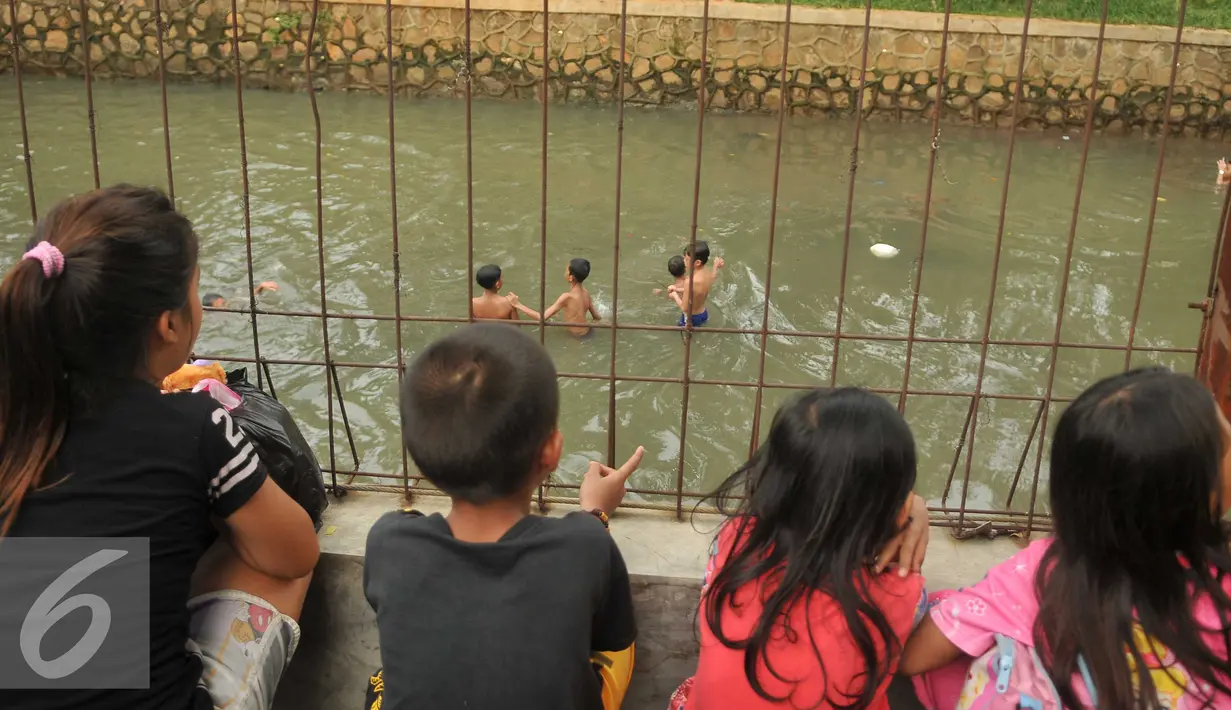 Sejumlah anak melihat temannya bermain di Anak Sungai Ciliwung di Jalan Labu, Kelurahan Mangga Besar, Jakarta, Selasa (17/5). Kondisi air yang mulai jernih dimanfaatkan mereka untuk bermain dan berenang. (Liputan6.com/Gempur M Surya)