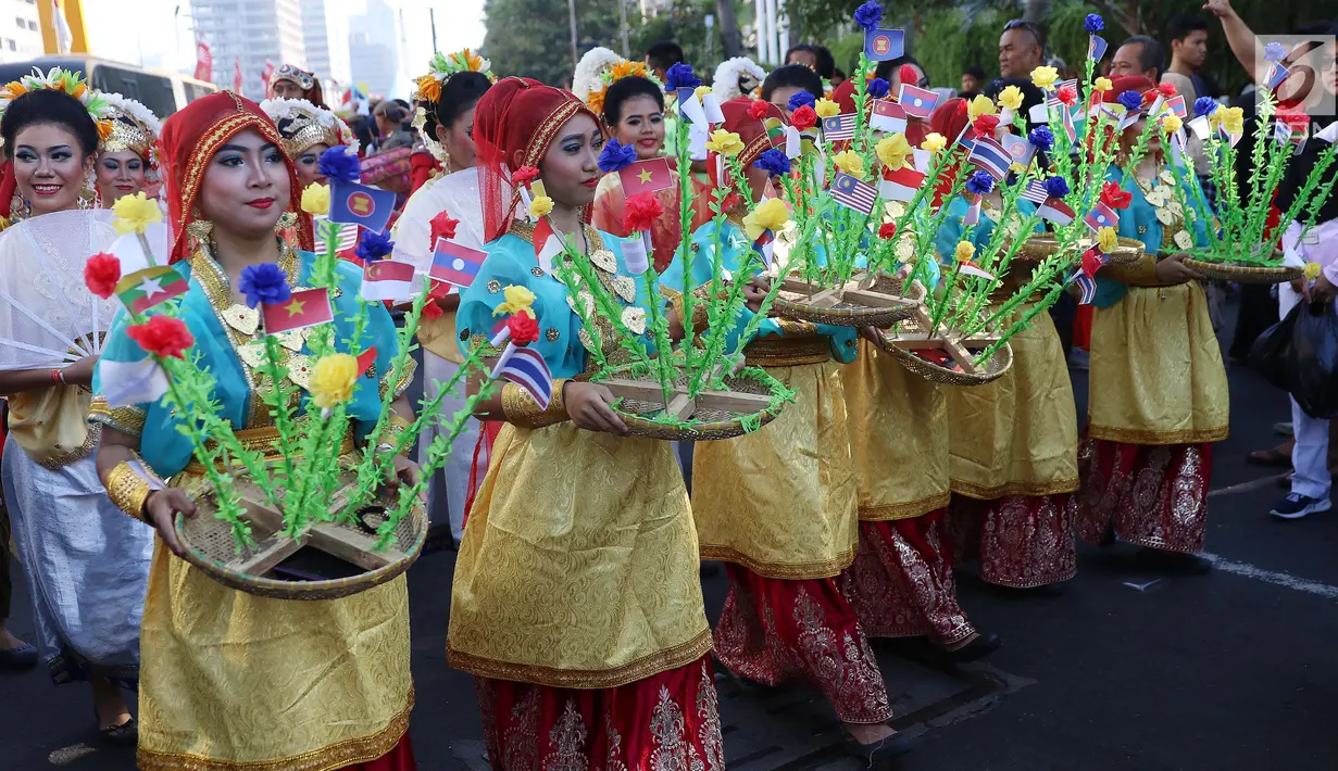 Peserta mengenakan baju adat membawa bendera negara anggota ASEAN saat parade ASEAN 50 Tahun di Jakarta, Minggu (27/8). Parade itu diikuti oleh seluruh negara yang tergabung dalam ASEAN. (Liputan6.com/Angga Yuniar)