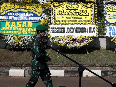 Prajurit TNI melintas di depan karangan bunga tanda duka cita atas meninggalnya mantan KSAD Jenderal TNI (Purn) Pramono Edhie Wibowo di kawasan Puri Cikeas, Kab Bogor, Jabar, Minggu (14/6/2020). Pramono Edhie Wibowo wafat di usia 65 tahun akibat serangan jantung. (Liputan6.com/Helmi Fithriansyah)