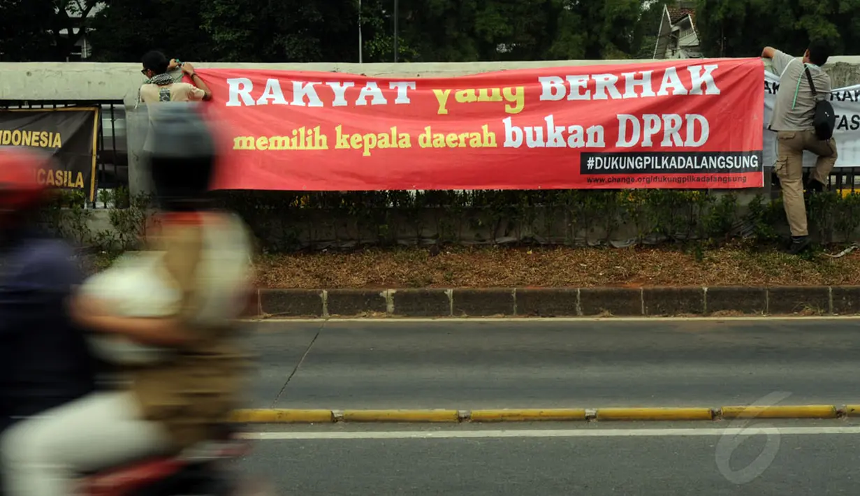 Beberapa aktivis membentang spanduk di pagar jalan tol dalam kota persis di depan gedung DPR RI, Jakarta, (14/10/2014). (Liputan6.com/Helmi Fithriansyah)
