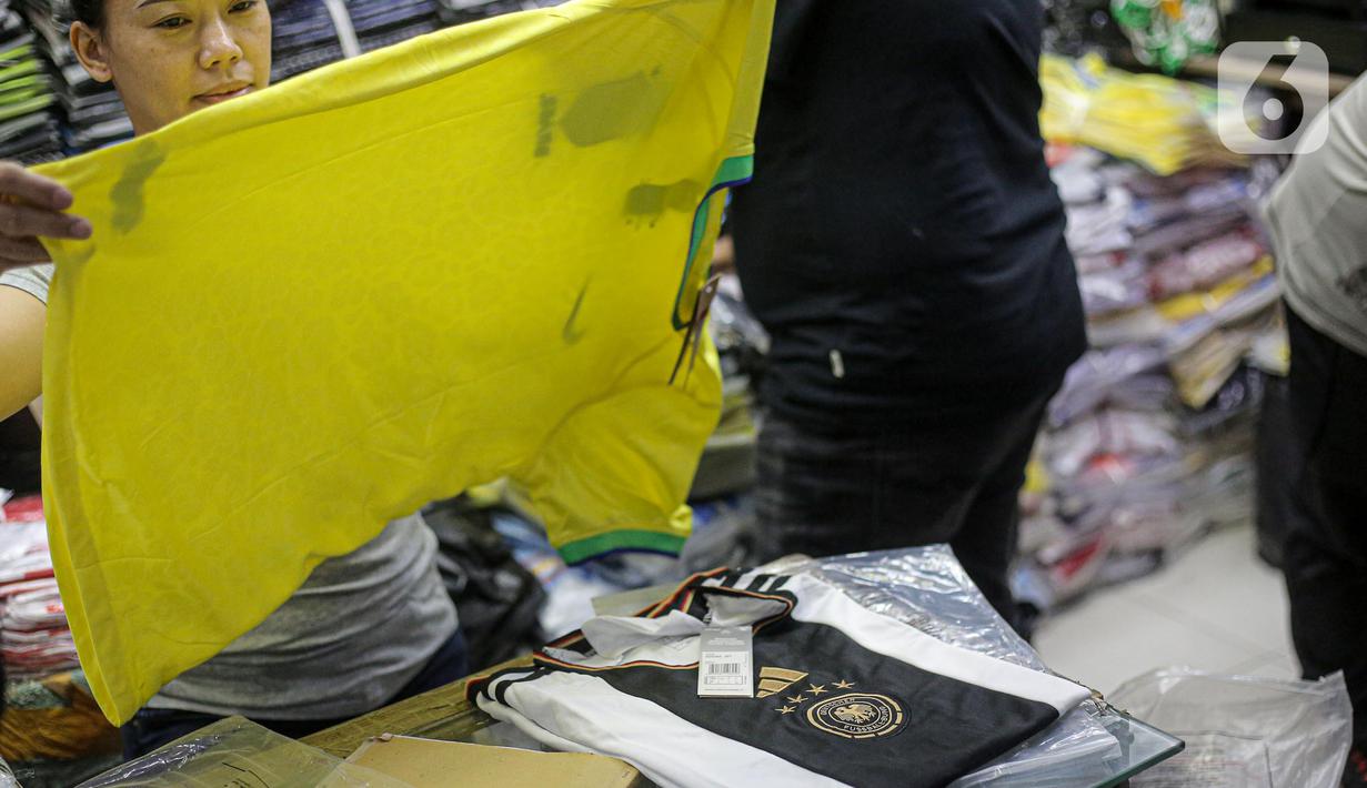 Pedagang melayani pembeli jersey tim Piala Dunia 2022 Qatar dipajang di salah satu kios di Blok B Pasar Tanah Abang, Jakarta, Jumat (18/11/2022). Turnamen sepak bola Piala Dunia 2022 Qatar yang akan berlangsung selama sebulan dan dimulai pada Minggu (20/11/2022) turut mendongkrak penjualan jersey. (Liputan6.com/Faizal Fanani)