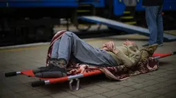 Seorang pasien lanjut usia menunggu di atas tandu untuk menaiki kereta evakuasi medis yang dijalankan oleh MSF (Doctors Without Borders) di stasiun kereta api di Pokrovsk, Ukraina timur, Minggu (29/5/2022). Kereta tersebut dilengkapi dikelola oleh tenaga medis, dan mengangkut pasien dari rumah sakit yang kewalahan di dekat garis depan, ke fasilitas medis di Ukraina barat, jauh dari pertempuran. (AP Photo/Francisco Seco)