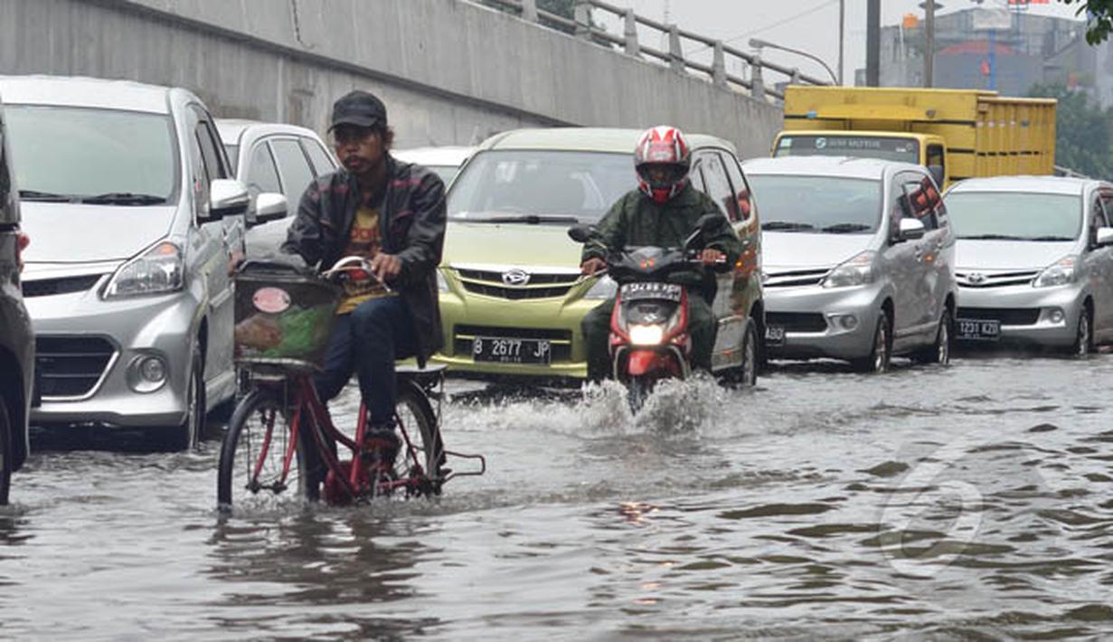 Sejumlah kendaraan memperlambat laju kendaraannya saat melintasi banjir, Minggu (1/2/2015). Hujan deras yang melanda sejak pagi menyebabkan jalan protokol Ibukota di Jalan Pramuka Jakarta, terendam banjir mencapai 20 cm. (Liputan6.com/Andrian M Tunay)
