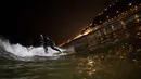 Ernesto Benavides meluncur ke dalam gulungan ombak saat berselancar di pantai La Pampilla, ibu kota Peru, Lima, 26 April 2017. Sekelompok peselancar hardcore memilih bermain selancar pada malam hari. (AP Photo/Rodrigo Abd)