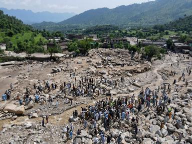 Pemandangan dari udara menunjukkan para korban banjir berkumpul di dekat rumah-rumah yang rusak di sepanjang tepi sungai yang dikelilingi batu-batu besar di distrik Buner, provinsi Khyber Pakhtunkhwa, Pakistan pada 17 Agustus 2025. (Abdul MAJEED/AFP)