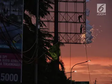 Dua pekerja memotong papan reklame yang telah tidak digunakan di kawasan Jalan TB Simatupang, Jakarta, Senin (11/2). Pemerintah Provinsi DKI Jakarta menganggarkan Rp 11 miliar untuk penertiban reklame ilegal. (Liputan6.com/Faizal Fanani)