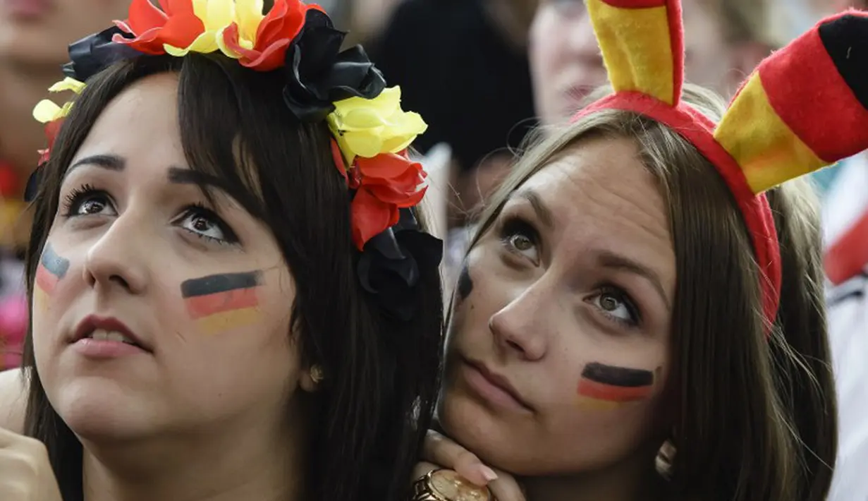 Bandana khas warna bendera Jerman dikenakan para fans cantik ini saat menyaksikan tim kesayangannya melawan Amerika Serikat di sebuah layar raksasa di Berlin pada 26 Juni 2014 (AFP PHOTO/CLEMENS BILAN)