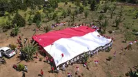 Pembentangan Bendera Merah Putih raksasa oleh puluhan eks napiter di Kabupaten Poso, Jumat (16/8/2024). (Foto: Satgas Madago Raya).