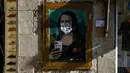 Poster seniman Italia TVBOY yang menggambarkan Mona Lisa karya Leonardo da Vinci mengenakan masker dan memegang smartphone di jalan Barcelona, Selasa (18/2/2020). Instalasi muncul setelah Mobile World Congress (MWC) 2020 batal digelar lantaran wabah virus corona yang mencekam. (PAU BARRENA/AFP)