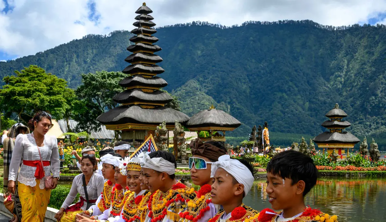 Pura Ulun Danu Beratan juga dikelilingi oleh taman hijau yang terawat rapi, menyediakan area yang nyaman untuk bersantai dan menikmati keindahan alam. Tampak dalam foto, sejumlah pemuda bersiap mengikuti prosesi keagamaan di Pura Ulun Danu Beratan, sebuah pura Hindu di Danau Beratan dekat Bedugul, Bali, pada Jumat 7 November 2025. (Mladen ANTONOV/AFP)