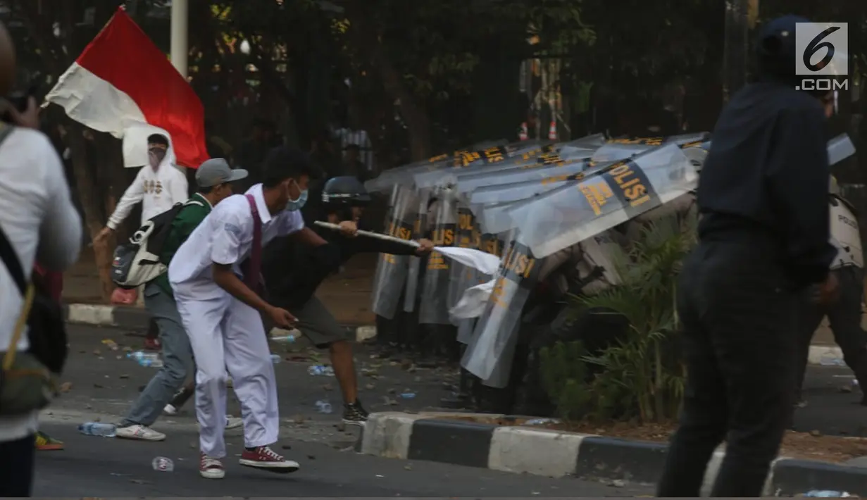 Massa melemparkan batu ke arah barisan polisi dalam unjuk rasa di sekitaran Gedung DPR RI, Jakarta, Senin (30/9/2019). Kericuhan pecah lantaran massa yang kebayakan terdiri dari pelajar tersebut berusaha masuk ke area depan DPR. (Liputan6.com/Johan Tallo)