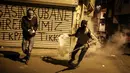 Dua militan Kurdi bersiap melemparkan tabung gas air mata ke arah polisi anti huru hara Turki dalam bentrokan di distrik Okmeydani, Istanbul (15/12/2015). Bentrokan terjadi karena pemerintah memberlakukan pembatasan jam malam. (AFP Photo/ Cagdas Erdogan)