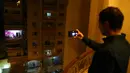 Warga mengabadikan foto konser biola yang digelar dari atas balkon di Kairo, pada 31 Maret 2020. Setiap malam, pemain biola asal Mesir Mohammed Adel menampilkan konser dari balkonnya untuk menghibur para tetangga selama jam malam nasional yang diberlakukan akibat COVID-19. (Xinhua/Ahmed Gomaa)