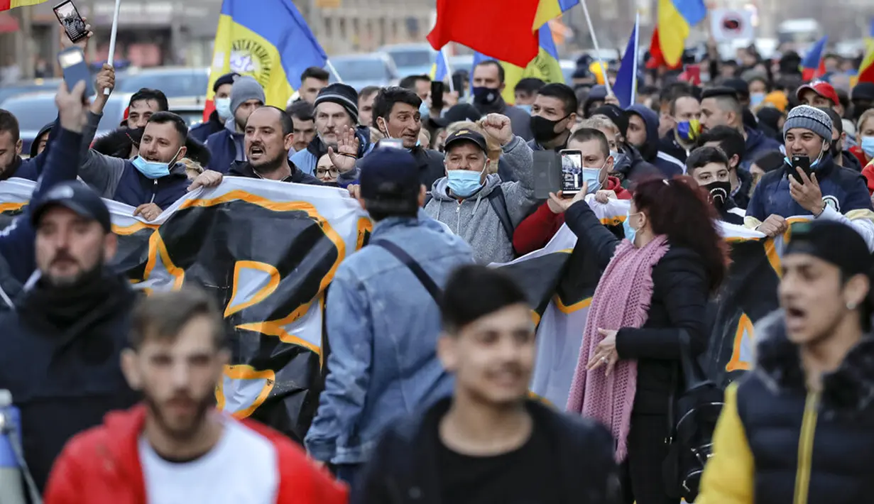 Warga yang memprotes pembatasan terkait pandemi COVID-19 berbaris di pusat Kota Bucharest, Rumania, Senin (29/3/2021). Ribuan pengunjuk rasa antipembatasan turun ke jalan di beberapa kota Rumania sehari setelah langkah pembatasan baru diberlakukan. (AP Photo/Vadim Ghirda)