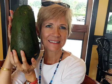 Dalam foto 28 November 2017 memperlihatkan seorang wanita Hawaii, Pamela Wang berpose dengan buah alpukat super jumbo yang ditemukannya di Kealakekua. Pamela menemukan alpukat seberat 2,3 kg yang seukuran dengan kepalanya. (AP Photo/Mary Lou Knurek)